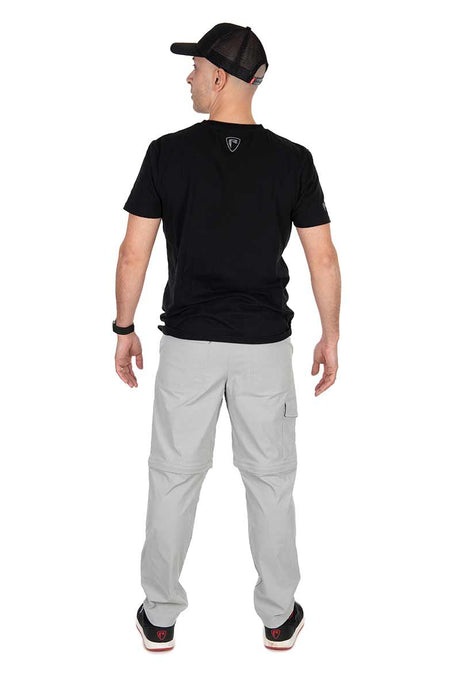 Hombre de espaldas con pantalón desmontable Fox Rage en gris claro y camiseta negra, ideal para pesca.